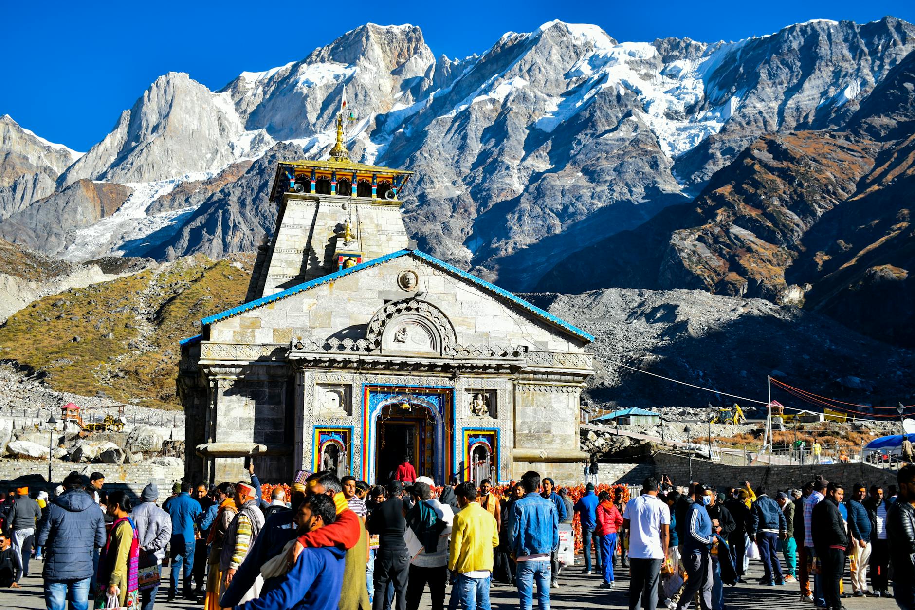 a group of people outside Kedarnath Temple with a mountain in the background